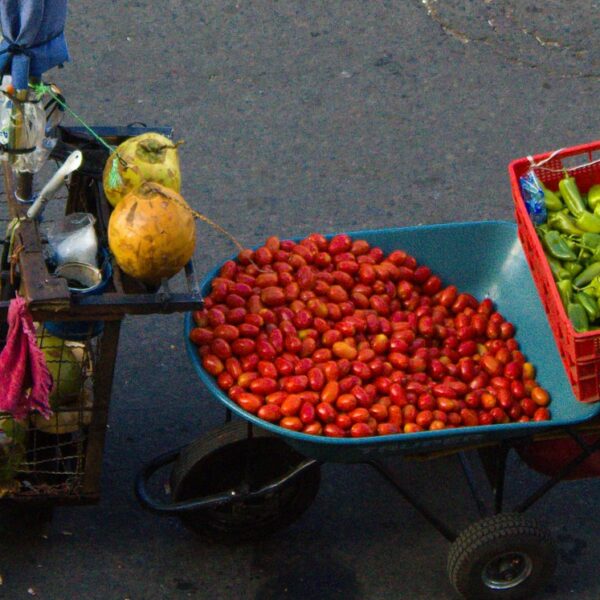 A man carries tomatoes and other fruits through a San Salvador street. Photo credit: Monica Mora via Flickr.